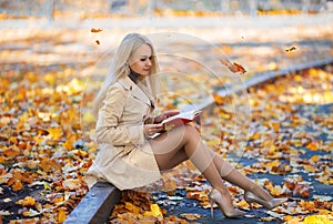 Student girl reading book in the autumn park