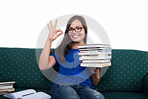 Student girl sitting on couch showing ok holding books