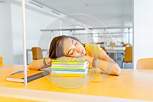 Student girl sleeping on the stack of books in the library. Deadline and exam concept