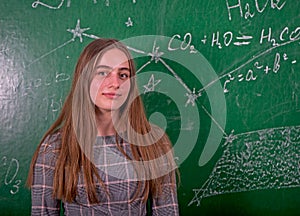 Student girl standing near clean blackboard in the classroom