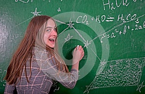 Student girl standing near clean blackboard in the classroom