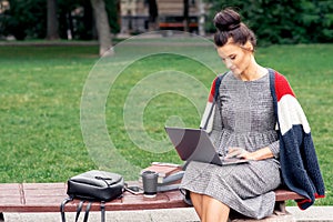 Student girl is studying on a laptop at park.