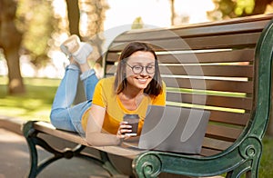 Student Girl Using Laptop Computer Lying On Bench In Park