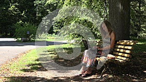 Student girl work with laptop sitting on bench in green park. 4K