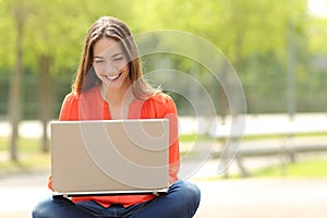 Student girl working with a laptop in a green park