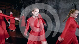 Student girls are dancing contemporary composition in a dark training hall in school of arts, jumping