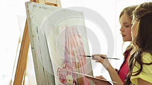 Student girls with easel painting at art school