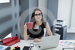 Student in glasses with a cup of coffee in the office