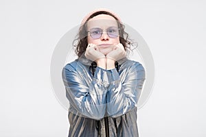 Student in glasses and silver jacket touching face with hand, looking annoyed, tired of listening uninteresting stories.