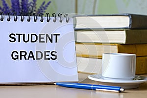 STUDENT GRADES - words in a notebook on a background of old books with pen and white cup