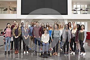 Student group standing in atrium under a big AV screen photo