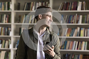 Student guy hold cellphone pose alone in university library