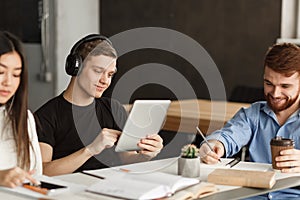 Student guy surfing net on tablet in library