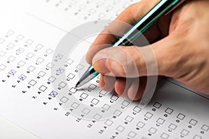 Student hand with pen fill in exam test answer sheet