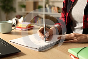 Student hand taking notes on notebook at night