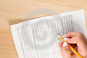 Student hand testing in exercise and passing exam carbon paper computer sheet with pencil in school test room, education concept