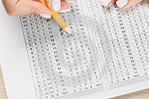 Student hand testing in exercise and passing exam carbon paper computer sheet with pencil in school test room, education concept