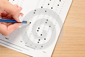 Student hand testing in exercise and passing exam carbon paper computer sheet with pencil in school test room, education concept