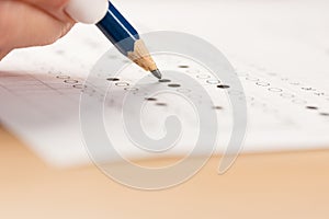 Student hand testing in exercise and passing exam carbon paper computer sheet with pencil in school test room, education concept