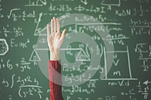 Student hand up behind green chalk board