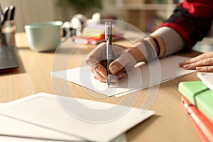 Student hand writing letter at home in the night