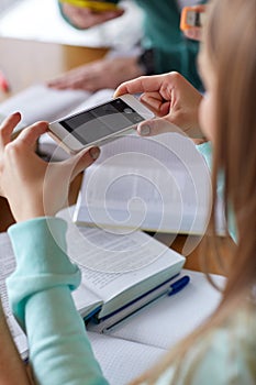 Student hands with smartphone making cheat sheet