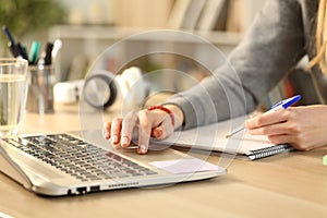 Student hands studying comparing notes with laptop photo