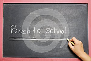 Student hands writing Back to School on the blackboard