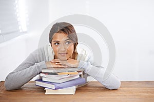 Student, happy and thinking with books by desk, idea and learning for research of assignment. Young woman, indian and