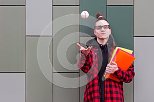 Student hold the books throws the ball looking at camera
