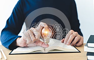 Student holding bright lightbulb and reading book or textbook. Success idea of education learning and studying. Businessperson