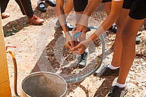 Student holding garden hose spraying fresh water to wash hands