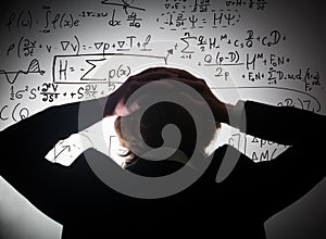 Student holding his head looking at complex math formulas on whiteboard. Problem to solve photo