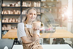 Student is holding a large clay cup in her hands