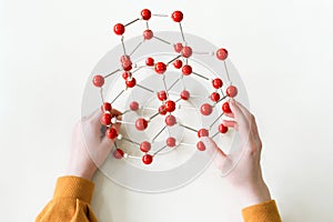 Student holding molecular structure model. Science class. Personal perspective view.