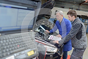 Student with instructor repairing car during apprenticeship