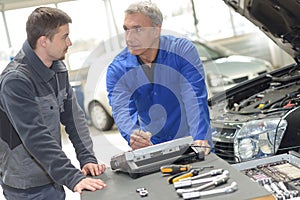 student with instructor repairing car during apprenticeship