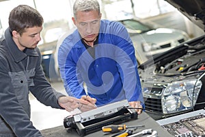 student with instructor repairing car during apprenticeship