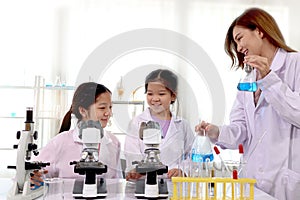 Student kids and teacher in lab coat having fun together while learning science experiment in laboratory classroom.