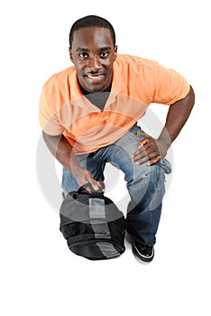 Student kneeling with a bag looking up smiling