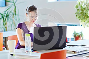 Student with laptop, books and papers, studying at home