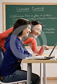 Student with laptop doing homework with friend