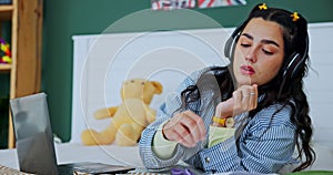 Student, laptop and girl with fidget toy for adhd, stress and writing notes on book in home bedroom. Music, headphones