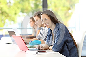 Student with laptop posing in a classroom