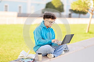 Student with laptop working outdoors, studying at park
