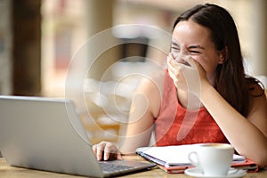 Student laughing e-learning in a bar