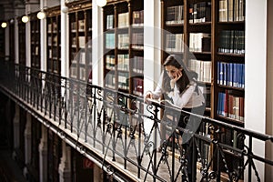 Student leaning and reading in library.