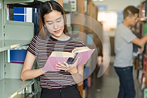 Student learning in library. Young read book in library for doing research assignment