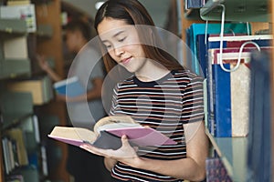 Student learning in library. Young woman read book in library for doing research assignment