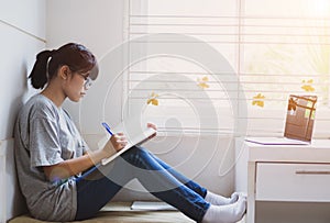 Student learning online study concept: Beautiful Asian girl learning and writing in notebook or homework, sitting short notes, use